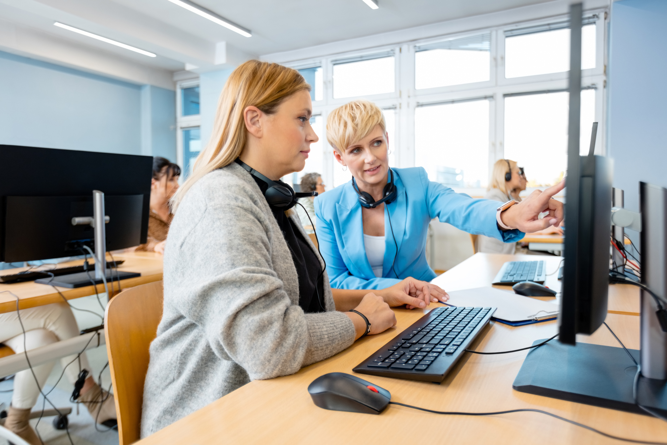 Female manager teaching employee on computer