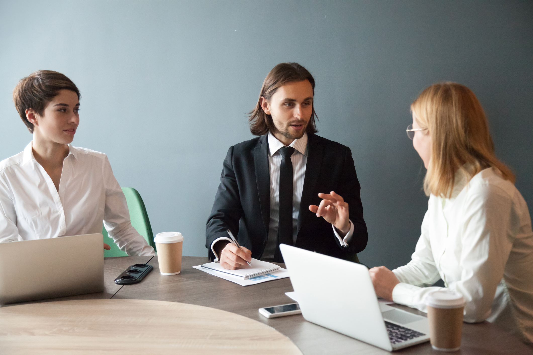 Confident millennial businessman sharing thoughts with female business partners