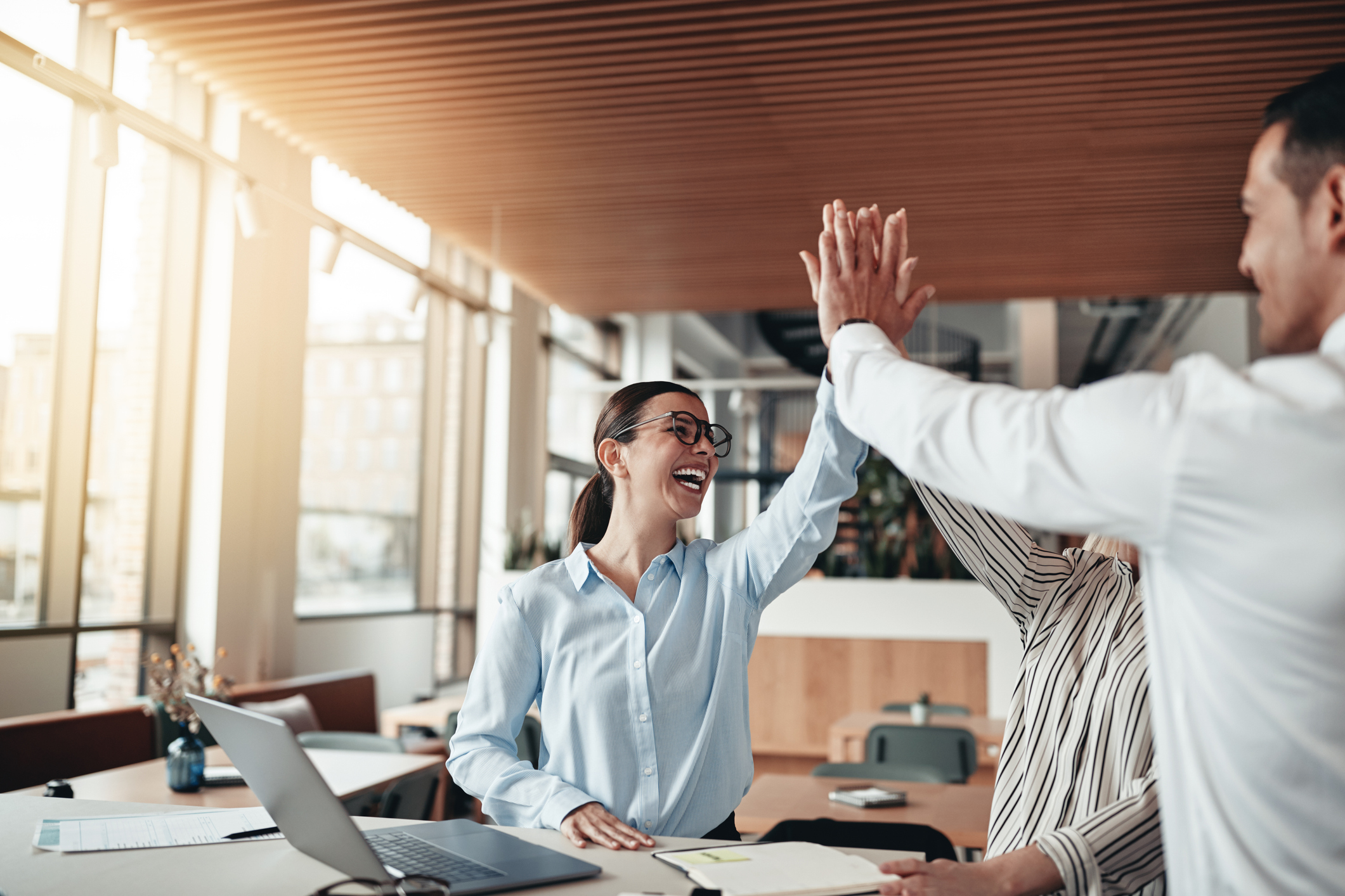 Businesspeople laughing and high fiving together in an office