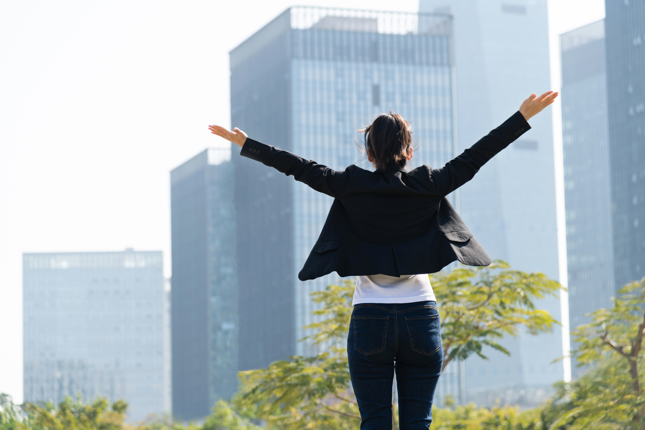 Businesswoman standing in front of skyscraper with arms outstretched