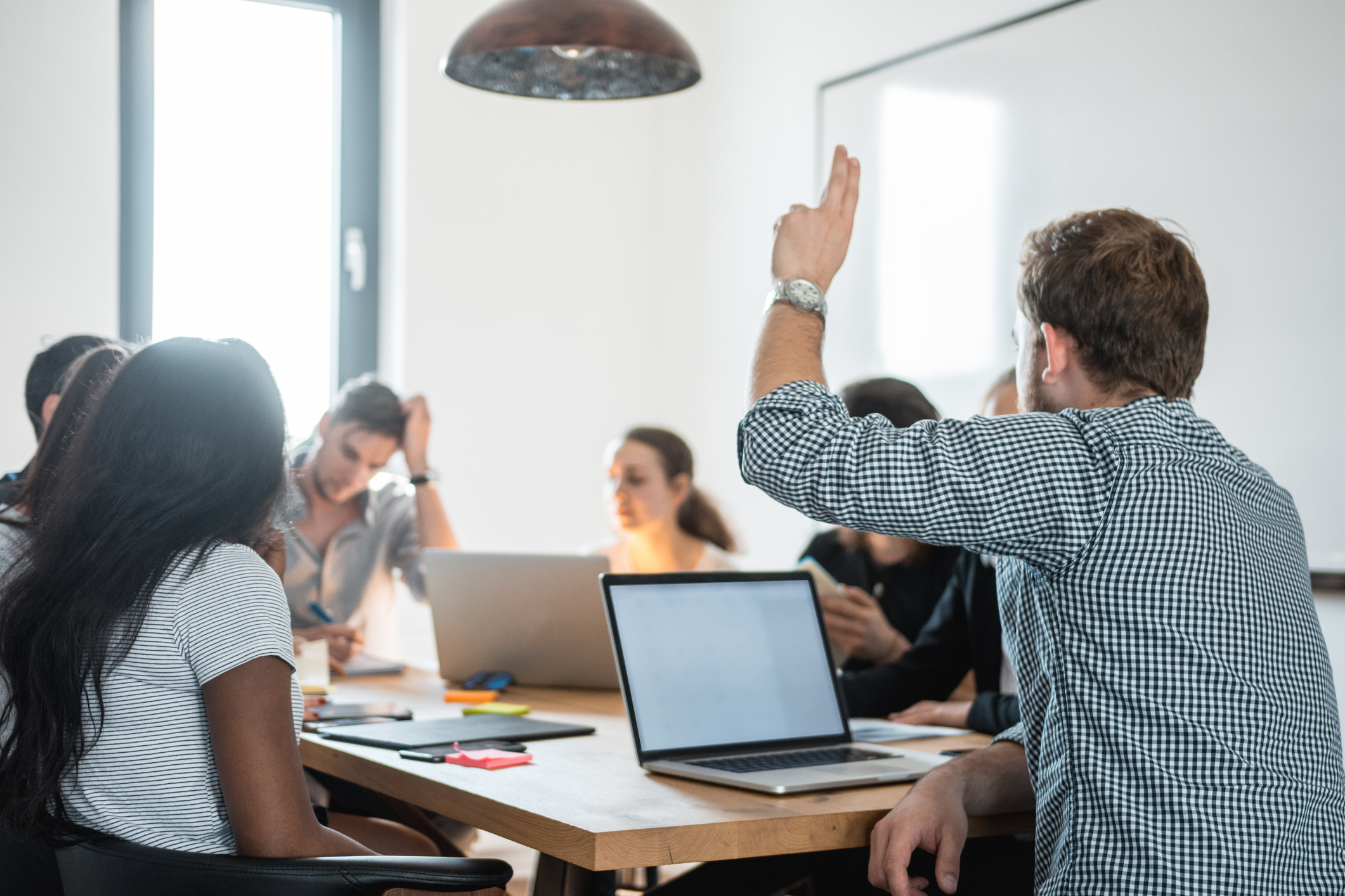 Businessman asking a question with raised hand in the conference room