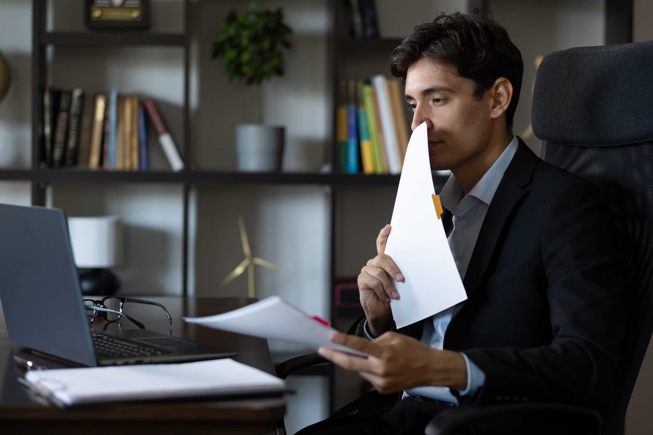 Young businessman in suit having online conversation with his documents