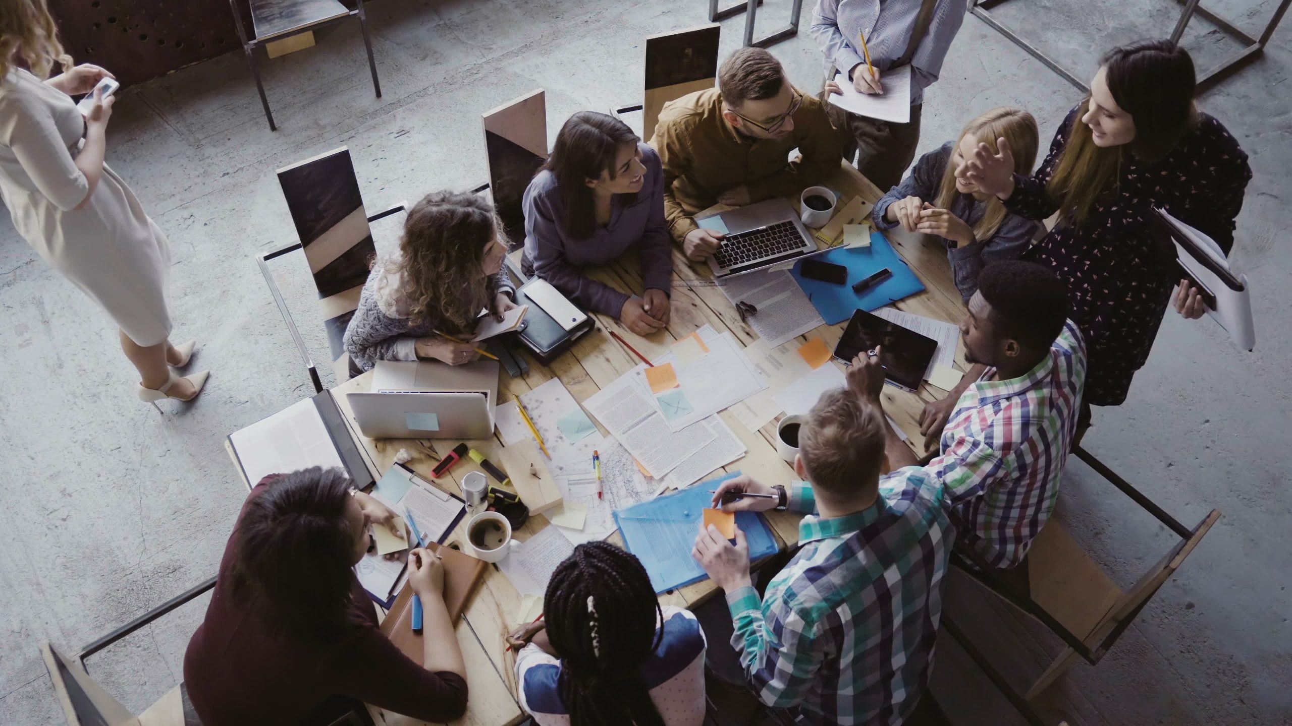 Business meeting at loft shared space. Multiethnic team talking, woman manager giving direction to people. Top view